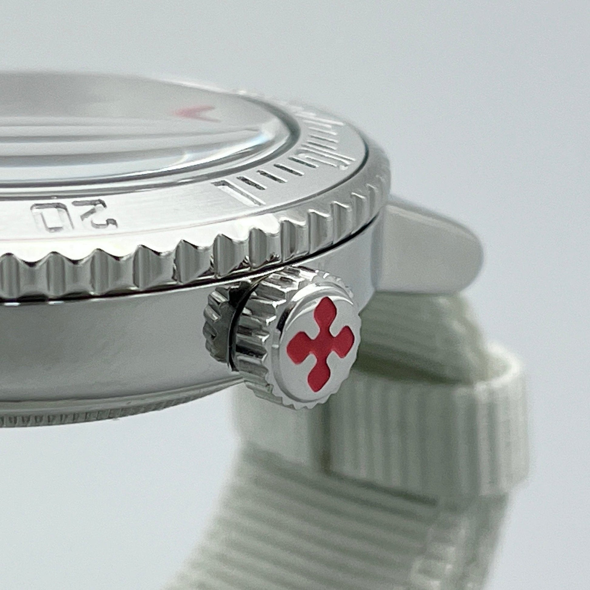 Closeup of crown on silver stainless steel dive watch with X logo