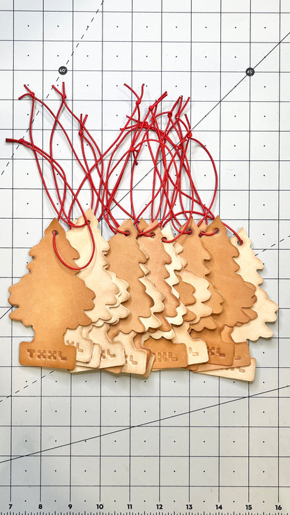 A stack of leather little tree car fresheners with TXXL logos